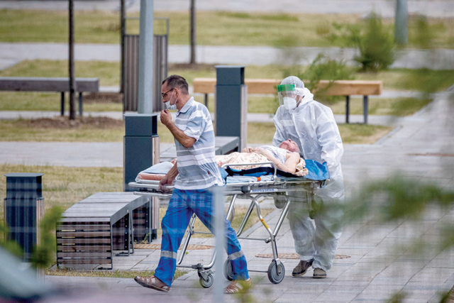 Medics escort a woman into a hospital where patients infected with the COVID-19 novel coronavirus are being treated in the settlement of Kommunarka outside Moscow on Wednesday. (AFP photo)
