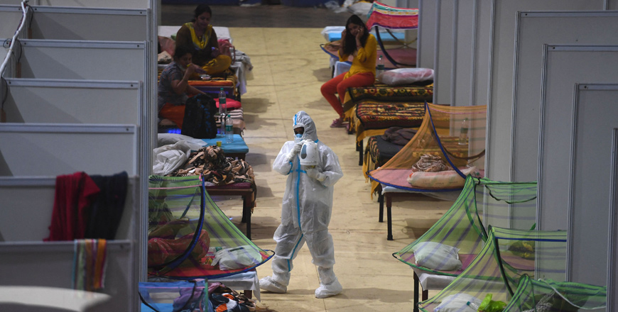 A health worker wearing a personal protective equipment suit attends COVID-19 coronavirus patients inside a centre of the Commonwealth Games village temporarily converted into a COVID care facility, in New Delhi, on Sunday (AFP photo)