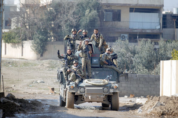 Members of the Iraqi rapid response forces ride a military vehicle during a battle with Daesh militants in the Mithaq district of eastern Mosul, Iraq, Thursday (Reuters photo)