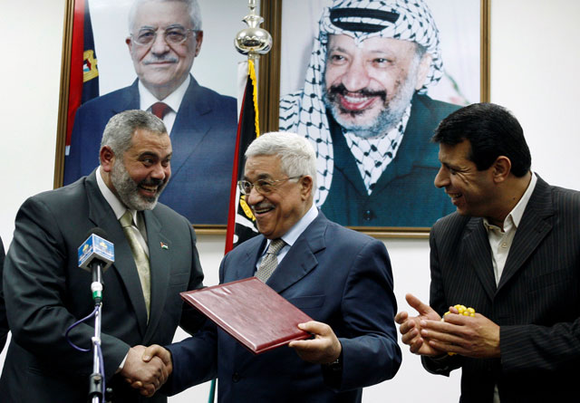 Palestinian President Mahmoud Abbas (centre) gives the letter of appointment to Prime Minister Ismail Haniyeh (left) as senior Fateh leader Mohammad Dahlan watches in Gaza, on February 15, 2007 (Reuters photo)
