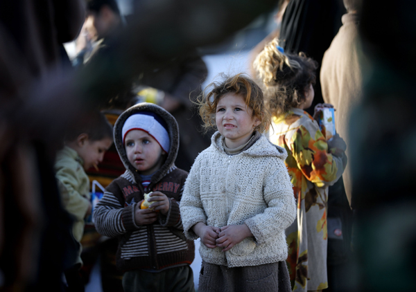 Displaced Iraqis who fled Mosul due to the ongoing fighting between Iraqi forces and extremists of the Daesh terror group receive food and drinks from volunteers of a NGO as they wait to be taken to a camp for displaced people, on Wednesday, in Bartalla, east of Mosul (AFP photo)