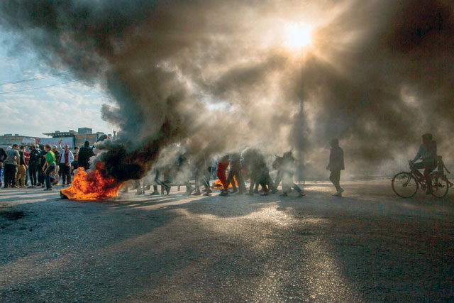 Smoke billows from burning tyres during a demonstration in the southern city of Basra on Sunday, as protesters cut-off roads and activists call for a general strike (AFP photo)
