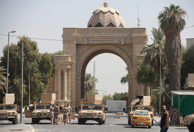 Iraqi forces stand guard as supporters and members of Saraya Al Salam (Peace Brigade), the military wing affiliated with Shiite cleric Moqtada Al Sadr, withdraw from Baghdad's Green Zone on Tuesday (AFP photo)