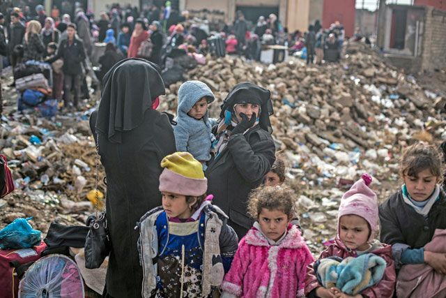 An Iraqi woman displaced from Mosul and her children wait at a gathering point for displaced people in Bartella, around 30km from Mosul, Iraq, on Monday (AP photo)