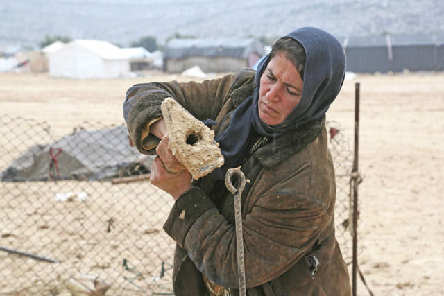 A Syrian woman who fled from the outskirts of southern Idlib due to conflict between government forces and opposition fighters puts up a shelter at the makeshift camp of Kalbeed near the Bab Al Hawa crossing on the Syria-Turkey border on Thursday (AFP photo)