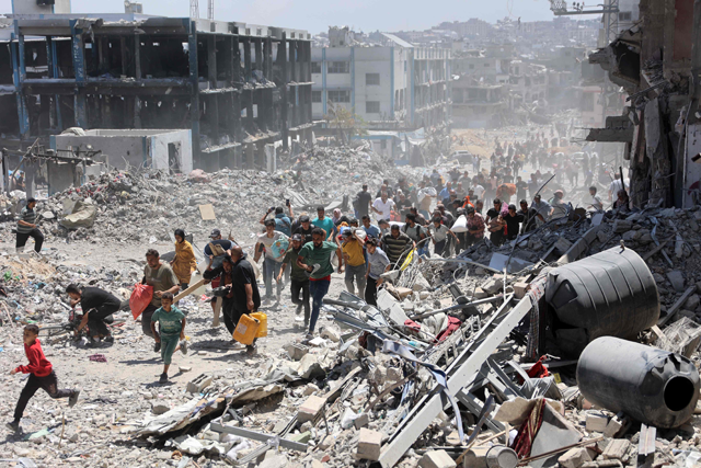 Palestinians who returned briefly to the Jabalia refugee camp in northern Gaza to check on their homes, run for cover after a school was hit by an Israeli strike on May 30, 2024, amid the ongoing Israeli war of aggression on the Strip (AFP photo)