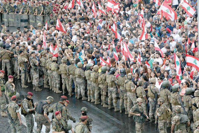 Anti-government protesters facing Lebanese army soldiers wave national flags in the area of Jal Al Dib on the northern outskirts of the Lebanese capital Beirut on Wednesday (AFP photo)