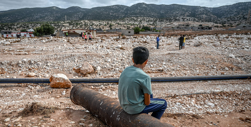 A boy watches as rescue teams search through the rubble in the eastern city of Soussa on Thursday, following deadly flash floods (AFP photo)