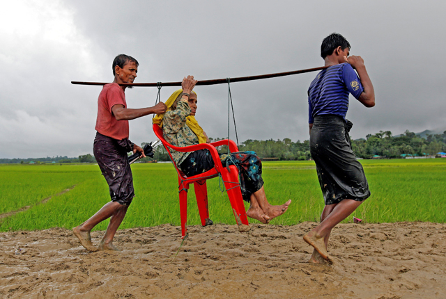 Rohingya refugee men carry an old woman as she is unable to walk after crossing the border in Teknaf, Bangladesh, on Friday (Reuters photo)