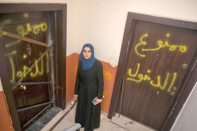 A Palestinian woman stands in front of sealed doors, with the words 'Entrance is prohibited' written in Arabic, of the family home of Palestinian Fadi Abu Shkhaydam — killed by Israeli forces last year — ahead of its demolition by Israeli occupation forces in the Shufat refugee camp in Jerusalem, on Tuesday (AFP photo)