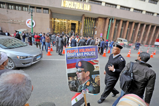 Supporters of Egyptian President Abdel Fattah Al Sisi hold a poster with his image in front of the National Election Authority in Cairo, Egypt, on Monday (Reuters photo)