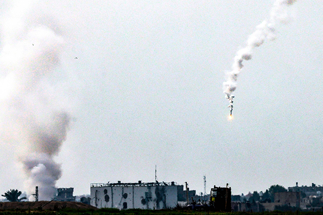 A photo taken from southern Israel near the border with the Gaza Strip on Sunday, shows smoke rising during bombardments as well as a flare fired by Israeli forces falling on Khan Yunis in the southern Gaza Strip, amid ongoing Israeli strikes against the besieged strip (AFP photo)