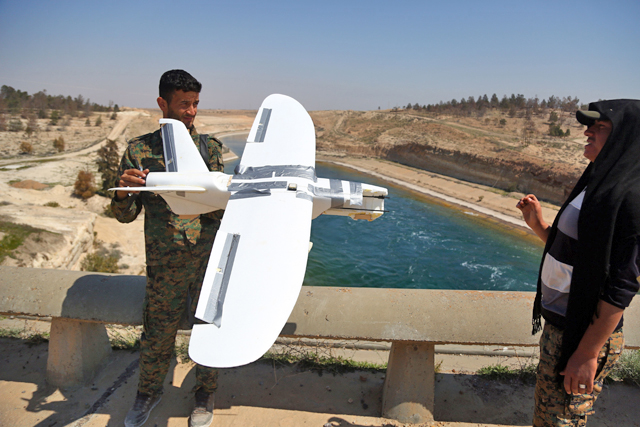 Members of the US-backed Syrian Democratic Forces (SDF), made up of an alliance of Arab and Kurdish fighters, inspect on Wednesday a downed drone, reportedly belonging to the Daesh group and being used to spy on SDF positions, at the Tabaqa Dam, Syria (AFP photo)