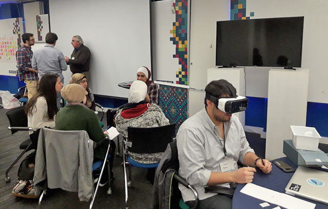 Teams of innovators exchange with representatives of NGOs while Yazan Fanous demonstrates the eyewear device used in his team’s project in Amman on Monday (Photo by Camille Dupire)