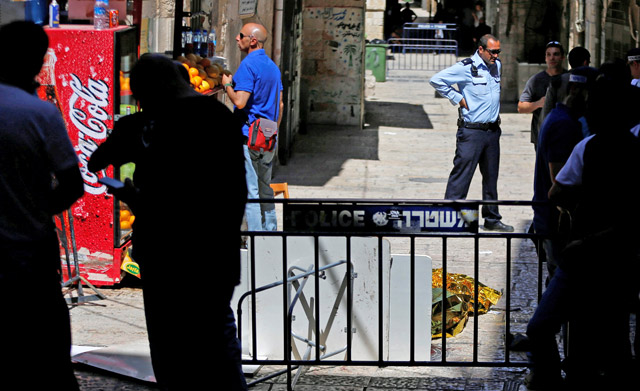 An Israeli occupation officer stands next to a covered dead body following an incident in the Old City of Jerusalem on Saturday  (Reuters photo by Ammar Awad)