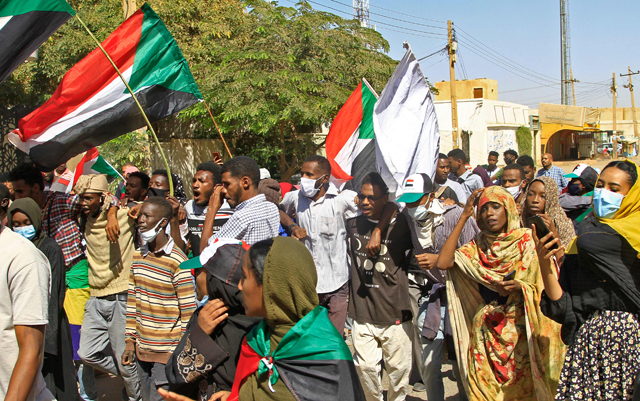 Sudanese demonstrators hold banners and wave their country's national flags during ongoing protests calling for civilian rule and denouncing the military administration, in the city of Khartoum North near the capital, on Monday (AFP photo)
