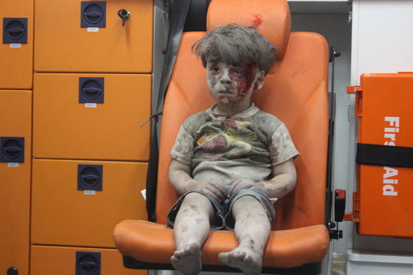 Omran, a four-year-old Syrian boy covered in dust and blood, sits in an ambulance after being rescued from the rubble of a building hit by an air strike in the rebel-held Qaterji neighbourhood of the northern Syrian city of Aleppo late on Wednesday (AFP photo)