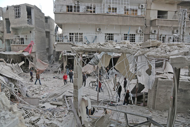 People inspect the debris of a building after Assad regime's warplanes allegedly carried out air strikes over residential areas of Kafr Batna town of the Eastern Ghouta region of Damascus in Syria on Monday (Anadolu Agency photo)