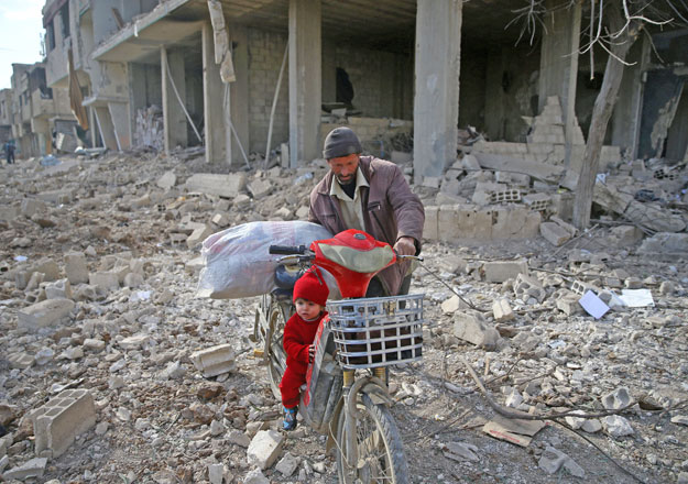 A man is seen with a child who rides a bicycle inside damaged area in Misraba, Eastern Ghouta, near Damascus, Syria, on Thursday (Reuters photo)