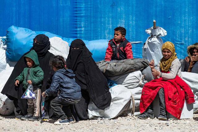 In this file photo taken on March 18, Syrian women and children sit by their belongings to wait for departure, as another group of Syrian families is released from the Kurdish-run Al Hol camp which holds suspected relatives of Daesh terror group fighters, in Hasakeh governorate of northeastern Syria (AFP photo)