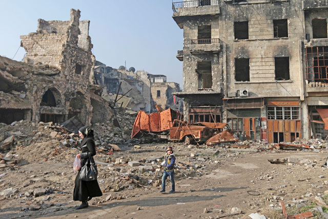 A Syrian woman walks with her daughter through the destruction in the old city of Aleppo, Syria, on Thursday (AP photo)