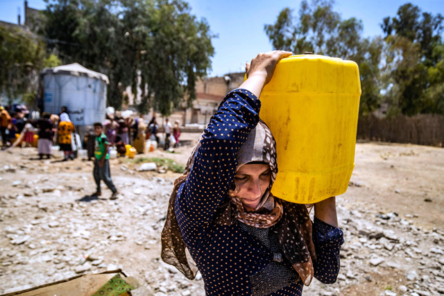 A Syrian woman carries a container of water provided by the UNICEF in Syria's northeastern city of Hasakeh, on July 8, after disruption in water supply from the Alouk station (AFP photo)