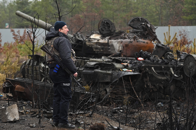 An Ukrainian policeman stands by the wreckage of a tank in Dmytrivka village, west of Kyiv, on Saturday as Ukraine says Russian forces are making a 'rapid retreat' from northern areas around Kyiv and the city of Chernigiv (AFP photo)