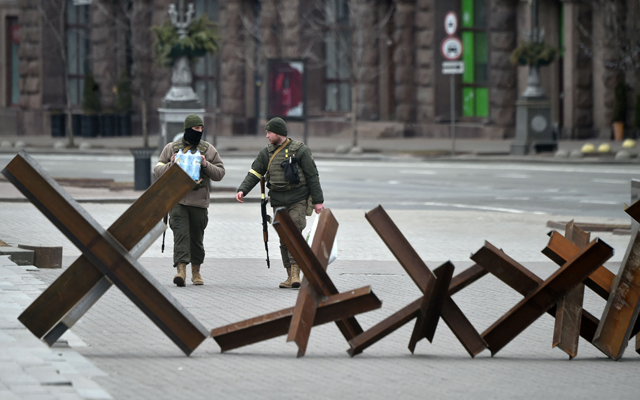 Members of the Ukrainian Territorial Defence Forces, the military reserve of the Ukrainian Armed Forces, walk past anti-tank structures blocking the streets of the centre of Kyiv on Sunday (AFP photo)