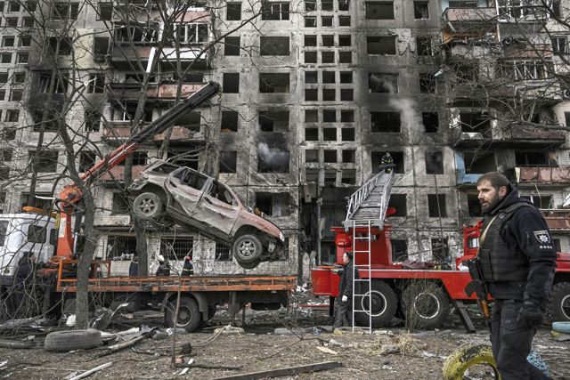 A crane removes a ruined car in front of a destroyed apartment building after it was shelled in the northwestern Obolon district of Kyiv on Monday (AFP photo)