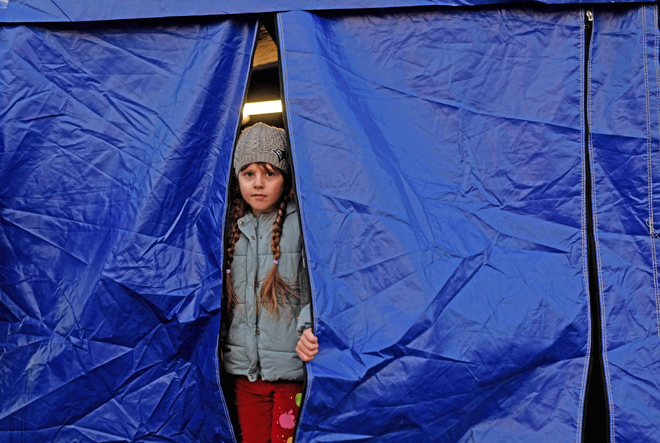 An Ukrainian child looks out of a tent while waiting for relocation after crossing the Ukrainian-Romanian border in Siret, northern Romania, on Saturday (AFP photo)
