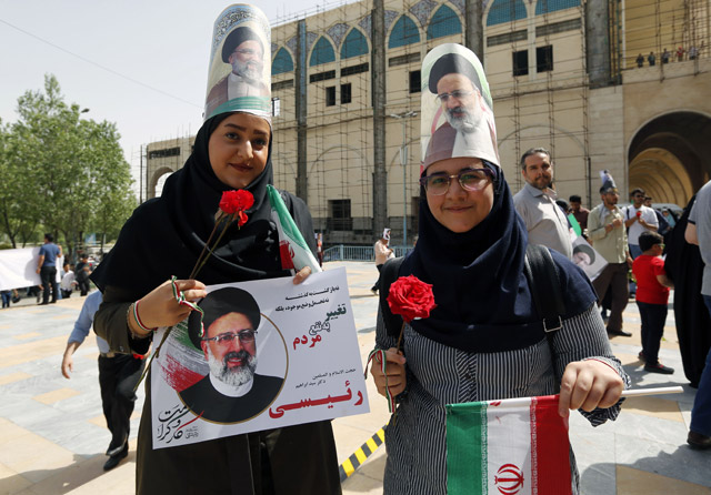 Supporters of Iranian presidential candidate Ebrahim Raisi hold his portrait and wear it on their heads outside a campaign rally at Imam Khomeini Mosque in the capital Tehran on Tuesday (Agence France-Presse photo)