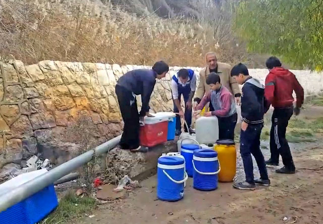 This frame grab from video provided By Yomyat Kzefeh Hawen Fi Dimashq (Diary of a Mortar Shell in Damascus), a Damascus-based media outlet that is consistent with independent AP reporting, shows Syrian residents filling up buckets and gallons of spring water from a pipe on the side of the road in Damascus, Syria (AP photo)