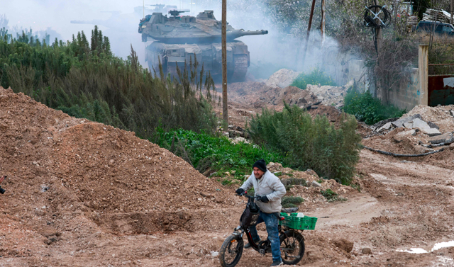 A man rides his bicycle as Israeli tanks enter the Jenin camp for Palestinian refugees in the occupied West Bank, on February 23, 2025 (AFP photo) 