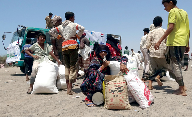 People displaced by conflict receive food aid donated by a Kuwaiti charity organisation in the village of Al Haima in the Khokha district of Yemen's war-ravaged western province of Hodeida, on Saturday (AFP photo)