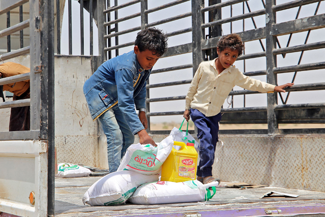 Yemenis displaced by the conflict receive food aid and supplies to meet their basic needs, at a camp in Hays district in the war-ravaged western province of Hodeidah on Tuesday (AFP photo)
