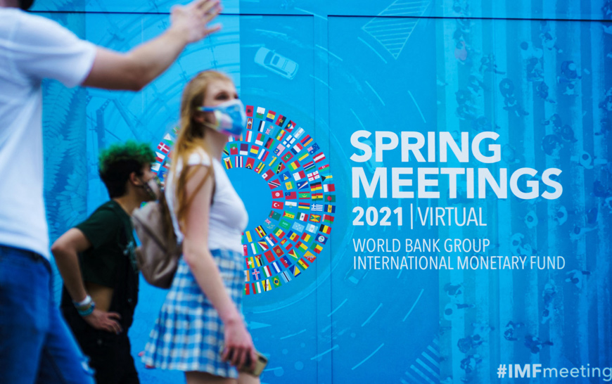   People pass by a banner for the World Bank Group/International Monetary Fund Virtual Spring Meetings in Washington, DC on Wednesday (AFP photo)