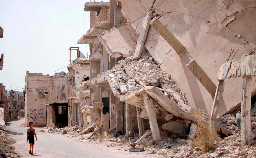 A Syrian child walks past the rubble of destroyed buildings in an opposition-held neighbourhood of the southern city of Daraa on Tuesday (AFP photo)
