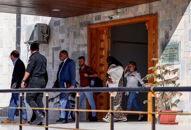 A Sudanese woman (2nd right) carrying a one-month-old baby, accused of joining the Daesh terrorist group,  being escorted by a Sudanese diplomat in Syria's northeastern city of Qamishli, after she was handed over by the Kurdish authorities, on Thursday (AFP photo)