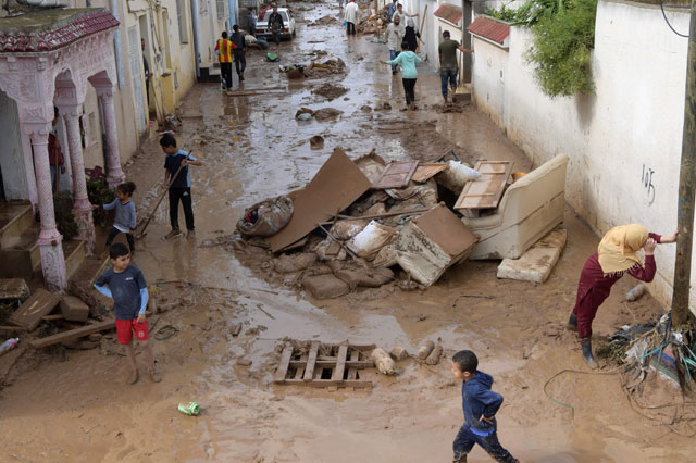 People walk in a mud-covered street that was flooded by torrential rains in the city of Mhamdia near the Tunisian capital Tunis on Thursday (AFP photo)