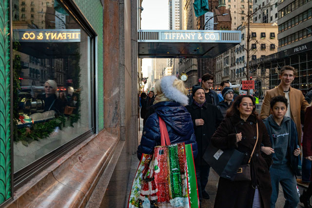 People with shopping bags walk down the sidewalk as the Christmas holiday approaches on Monday in New York City (AFP photo)