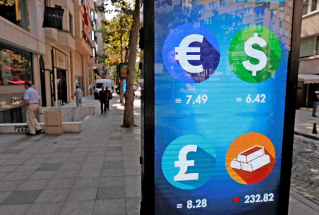 Pedestrians walk past an electronic board showing the currency exchange rates in Istanbul, Turkey, on Friday (Reuters photo)