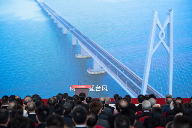 Guests watch a trailer on a giant screen during the opening ceremony of the Hong Kong-Zhuhai-Macau Bridge at the Zhuhai Port terminal on Tuesday (AFP photo)