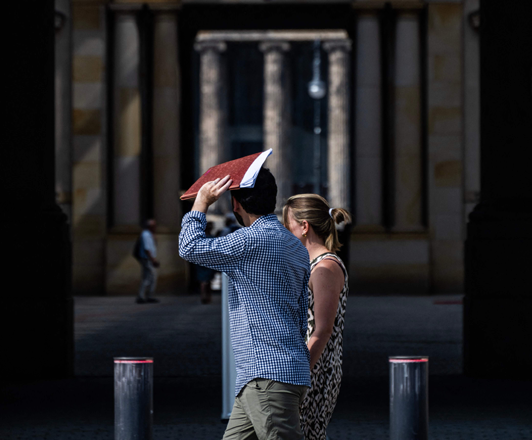 A man shields himself from the sun in front of the Humboldt Forum Museum as temperatures rose over 30ºC in the German capital, on Tuesday (AFP photo)