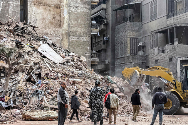 An excavator clears rubble from the site of a collapsed building in the Waili district of central Cairo on Monday (AFP photo)