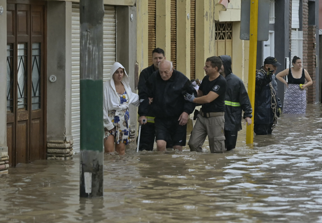 An elderly man is helped to evacuate a flooded area after a powerful storm struck the city of Bahia Blanca, 600 km south of Buenos Aires yesterday (AFP photo)
