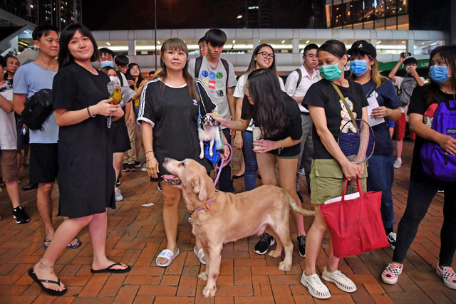 People watch as anti-extradition protesters gather at Kwai Fong MTR Station in Hong Kong, on Tuesday (AFP photo)