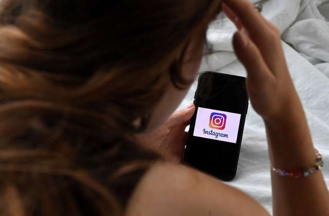 In this photo illustration, a person looks at a smart phone with an Instagram logo displayed on the screen, on August 17, 2021, in Arlington, Virginia (AFP file photo)