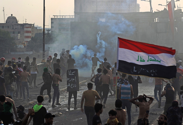 Iraqi protesters run from tear gas fired by security forces amid clashes following a demonstration on Al Jumhuriya Bridge in the capital Baghdad on Sunday (AFP photo)
