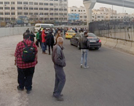 Commuters are seen waiting to board buses at a bus stop in Amman in this recent photo (Photo by Osama Aqarbeh)