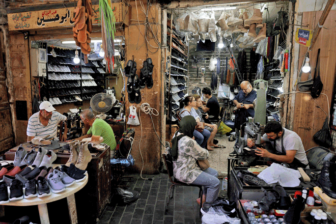 Workers repair shoes as customers wait in Ahmed Al-Bizri's shoe-repair store in the coastal city of Sidon on Tuesday (AFP photo)